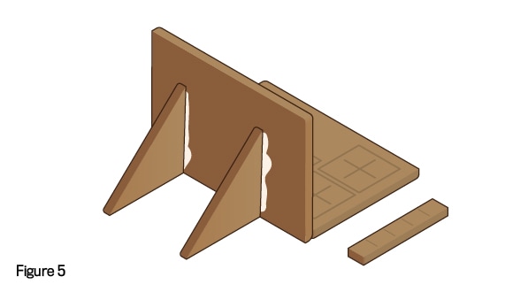 rear view, with triangle upper wall pieces stuck to back of piece with gingerbread person and tree to hold it up, with additional narrow piece of wall cut in router step 1 laying next to 'laptop'; text: figure 5
